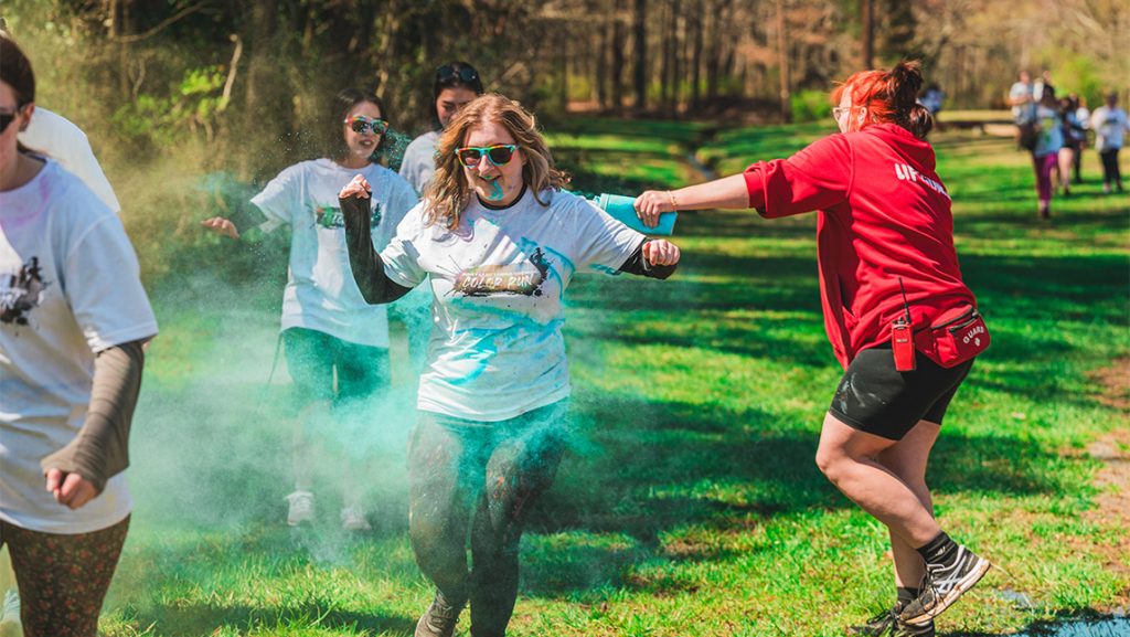 A Piney Lake staffmember shoots colored dye and UNCG students.