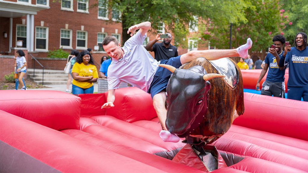 A UNCG student starts to fall off a mechanical bull.