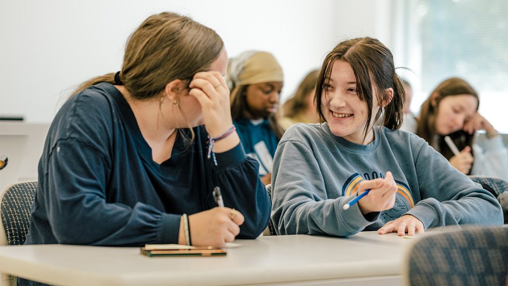 Students chat at a desk at UNCG.