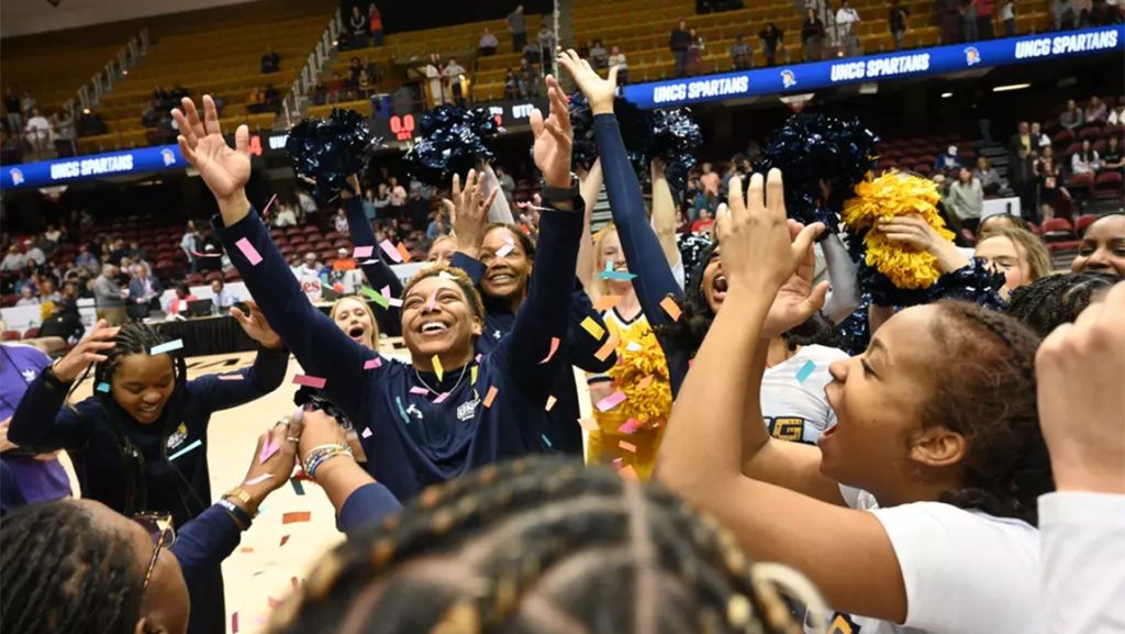 UNCG women's basketball celebrates on the court after SoCon 2025 win.