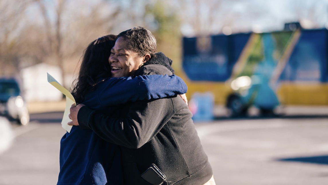 UNCG School of Nursing, Apel hugs one of the patients in the parking lot of the Minerva Health Mobile.