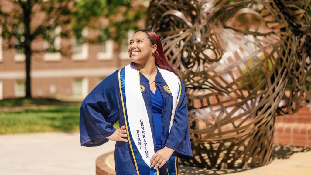 UNCG School of Nursing graduate Jyesha McKinney poses outside in front of Minerva statue.