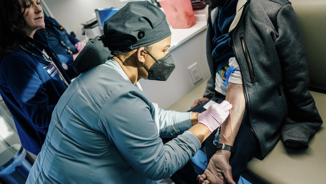 Mobile Health Scholar Harrison helping a patient in the Minerva Mobile. 