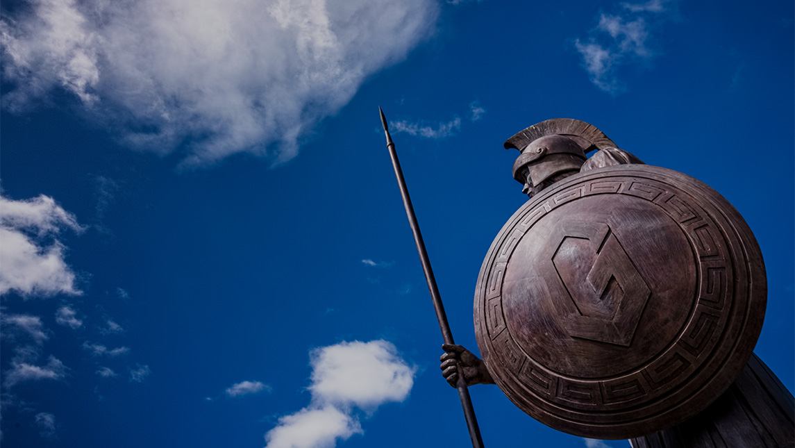 The UNCG Spartan statue against a blue sky.