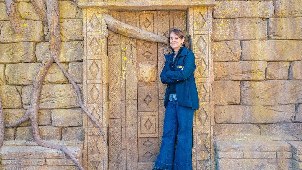 Crista McGee stands in front of a decorative gate on the North Carolina Zoo Asia entrance.