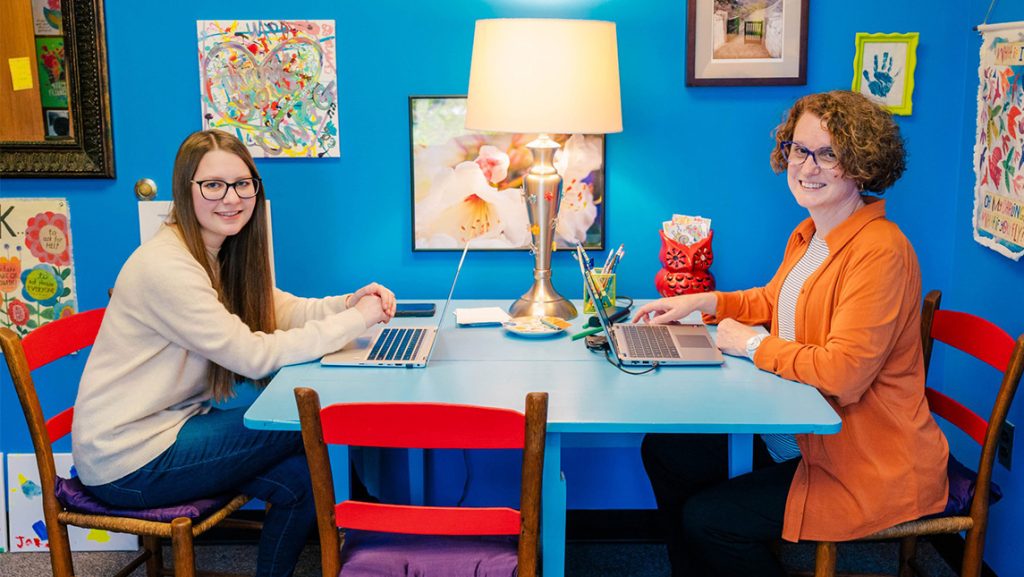UNCG's Kim Cuny sits at a table with a student.