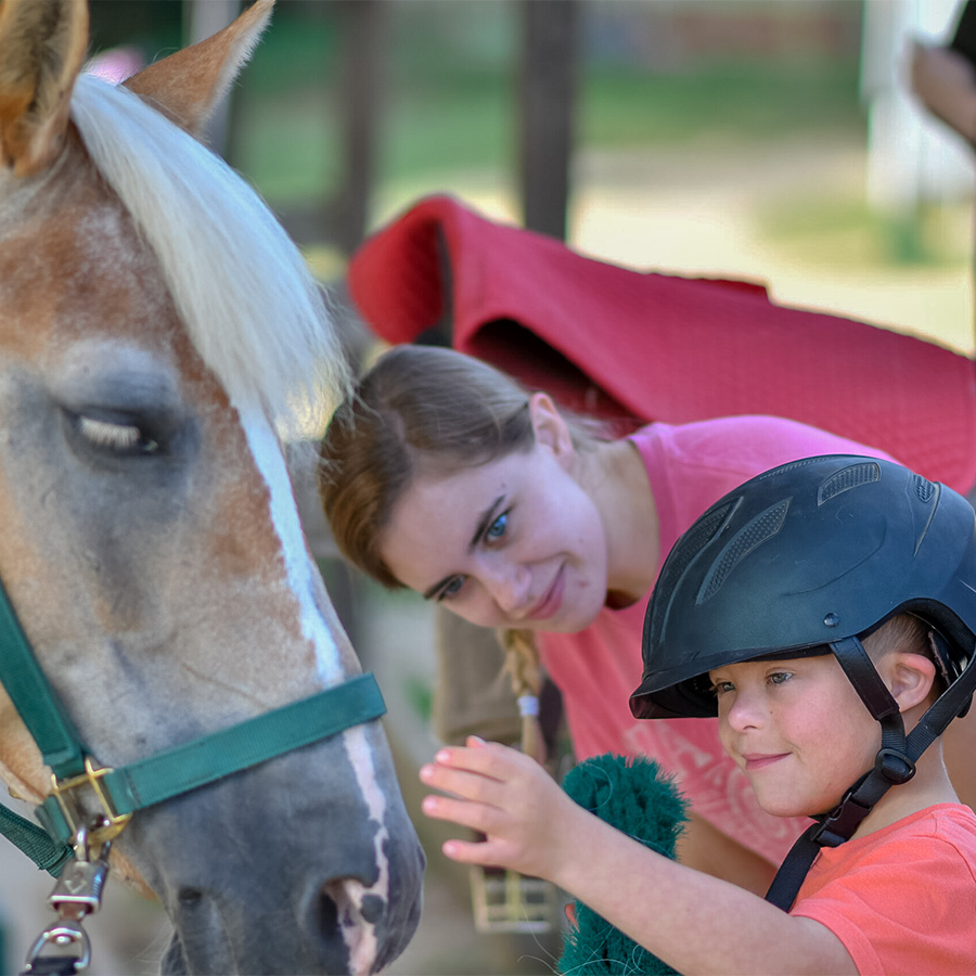 A child pets a horse during a UNCG-led camp.