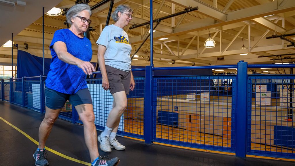 Two women walk the track around the UNCG Kaplan Center.