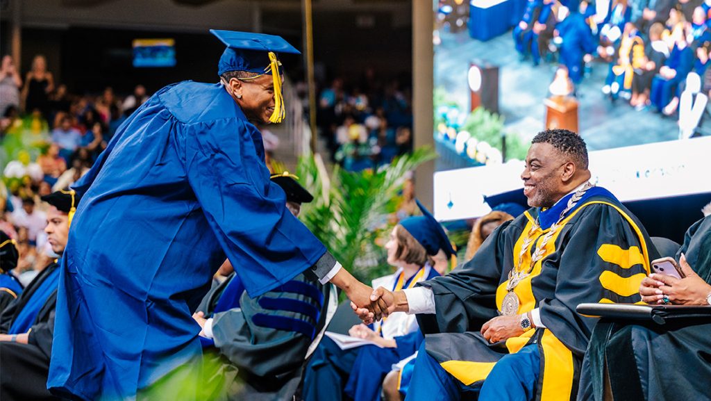 A UNCG student shakes Chancellor Gilliam's hand at Commencement.