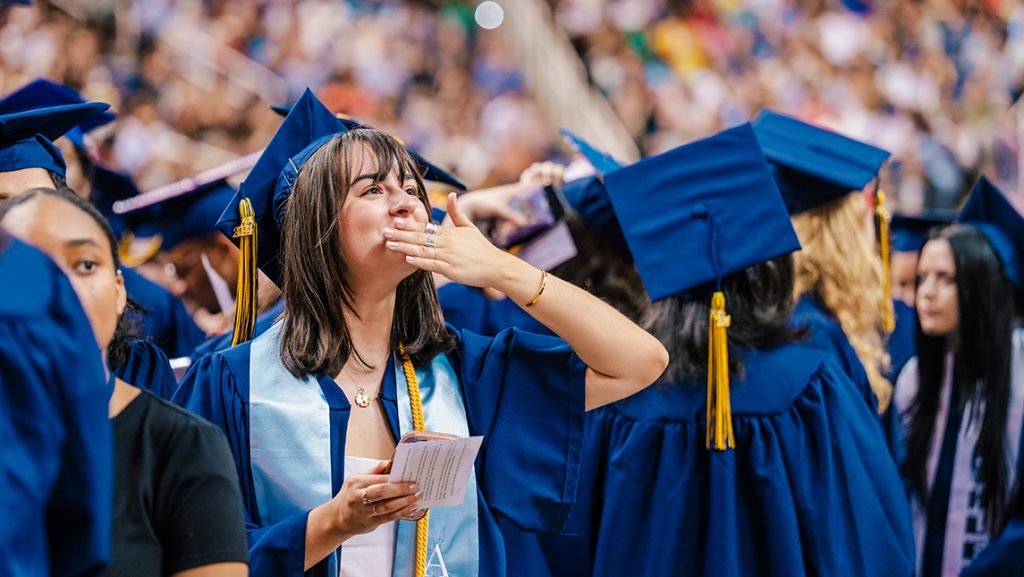 A UNCG student blows a kiss to family at Commencement.