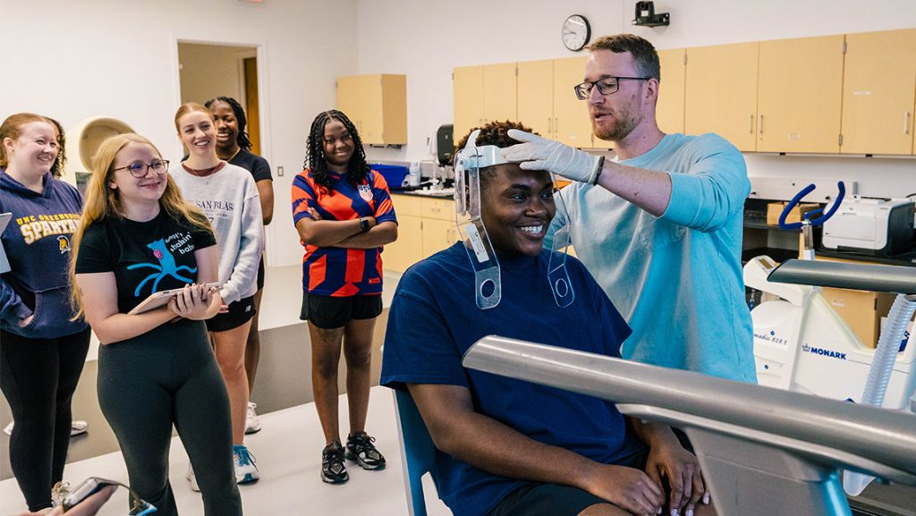 A UNCG kinesiology student fits a headband around a volunteer.