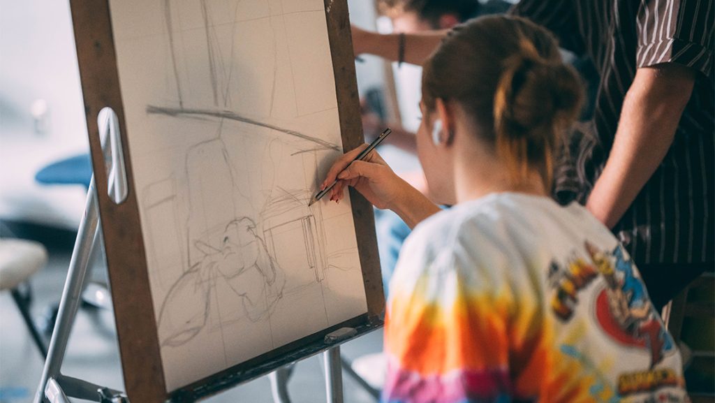 A UNCG student sketches on an easel.