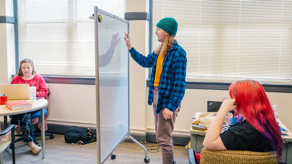 UNCG students work out problems on a whiteboard.