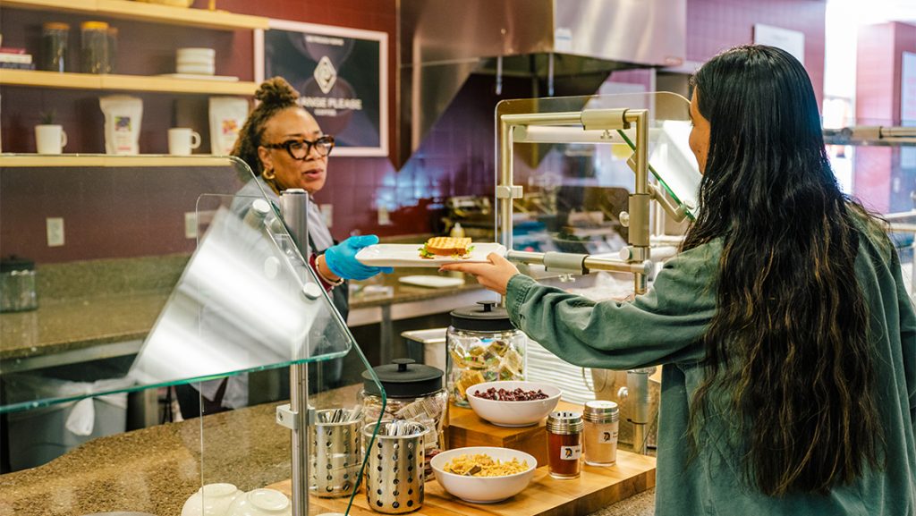 UNCG cafe worker hands a sandwich to a student.