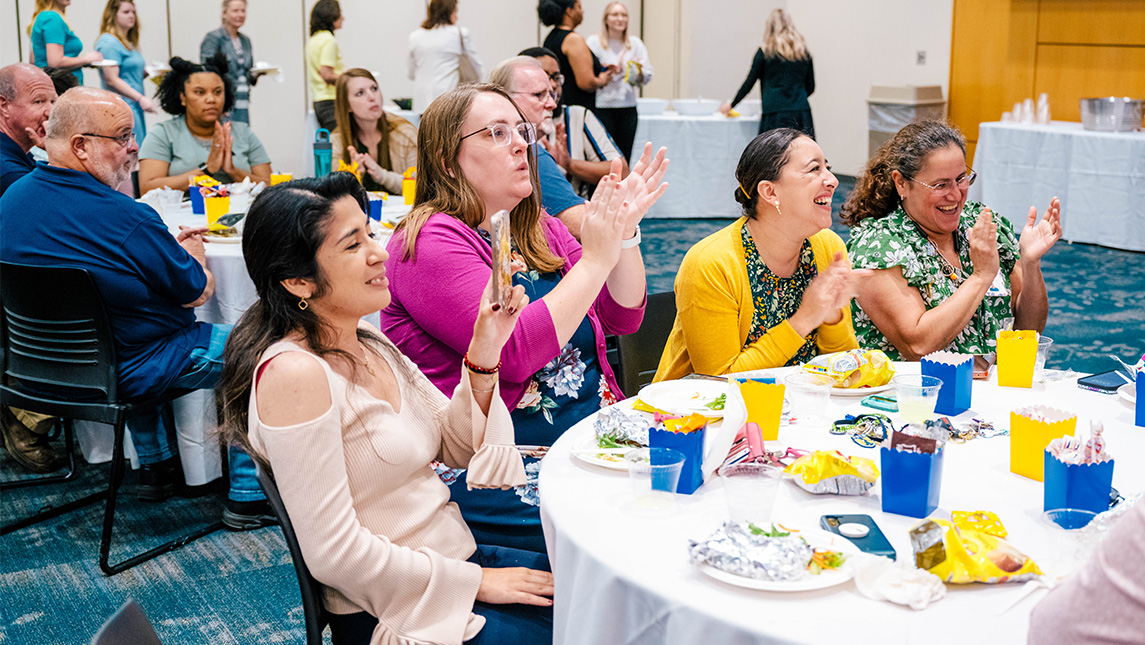 UNCG staffmembers applaud at a table.