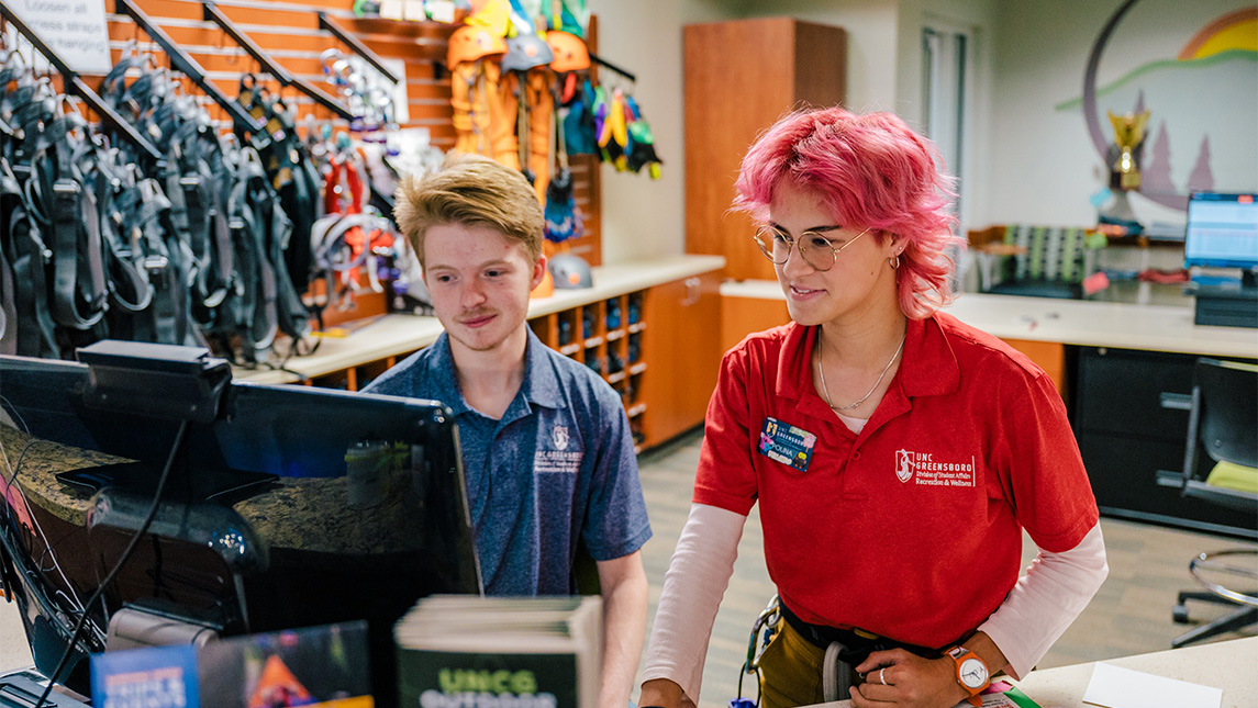 UNCG students working behind the desk at the bookstore.