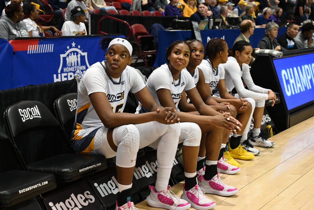 Khalis Cain with other basketball players watching from the sidelines.