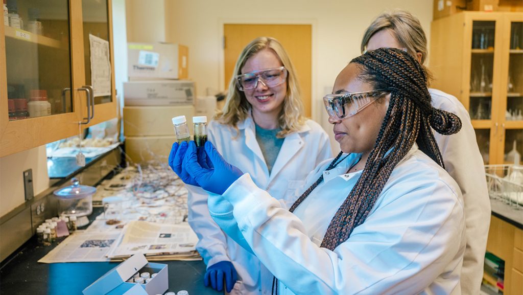 UNCG doctoral student Zoie Bunch watches Janae Wofford compare lab test tubes.