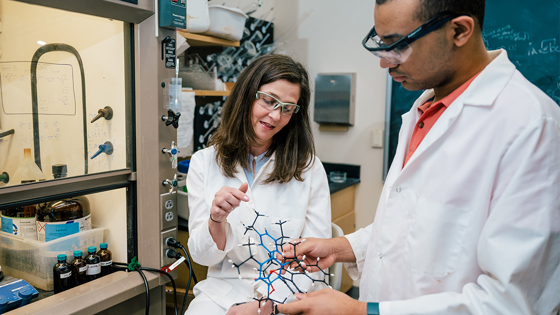 Dr. Kimberly Petersen shows a molecule model to a UNCG student.