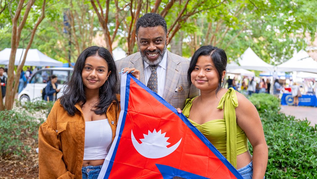 Two UNCG students hold a flag with Chancellor Gilliam.