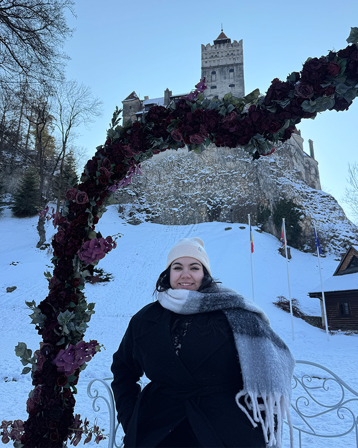UNCG alumna Grecia Nandin in front of a castle in the snow.