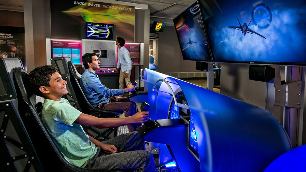 A boy and father sit in a virtual simulation of a fighter jet flight.