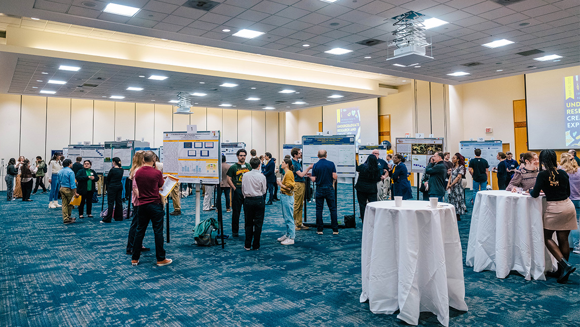 Students and judges mill about UNCG Cone Ballroom at the Undergraduate Research Expo.