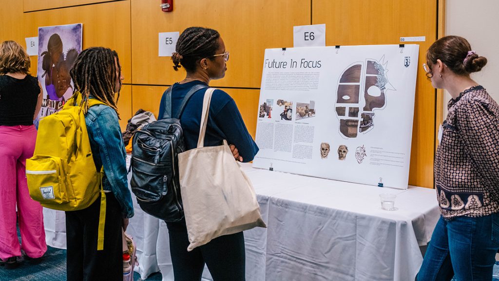 UNCG students look closely at a research poster on display.