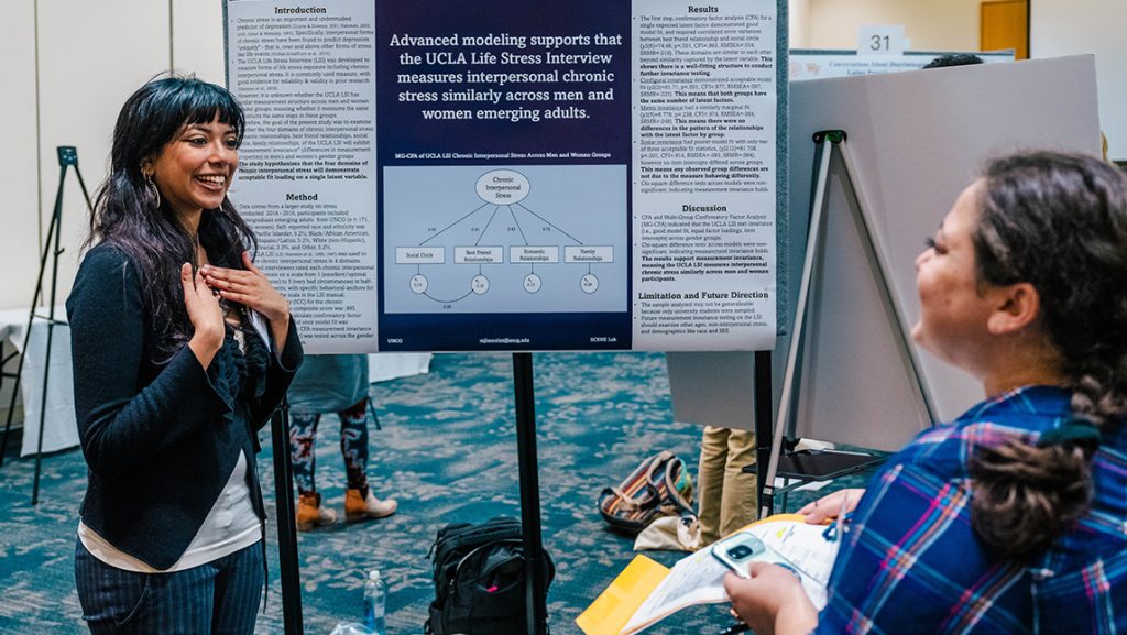 A student explains research on a poster.