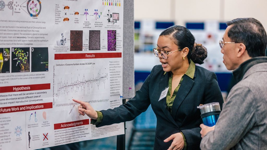 A UNCG student shows a judge data on her research poster.