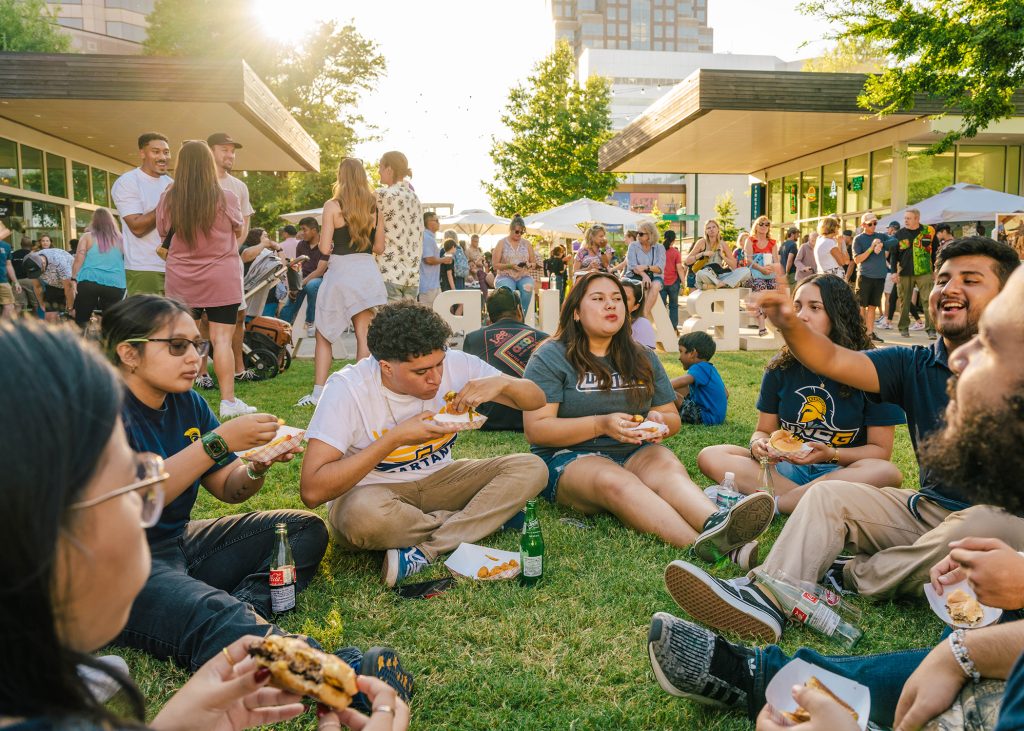 Students sit on the lawn at LeBauer Par and eat street food.