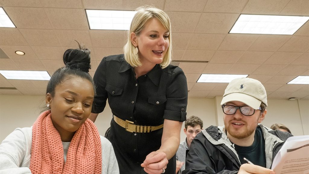 UNCG lecturer Sara MacSween looks over shoulders of students while they study.