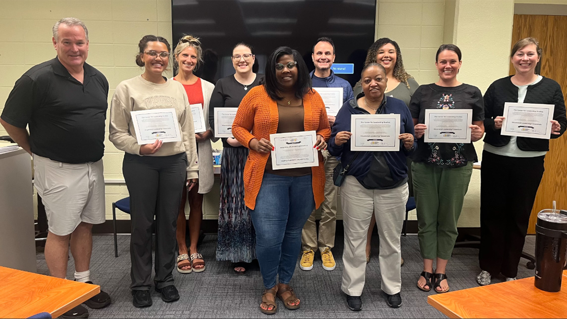UNCG's Student Leadership cohort holds up certificates.