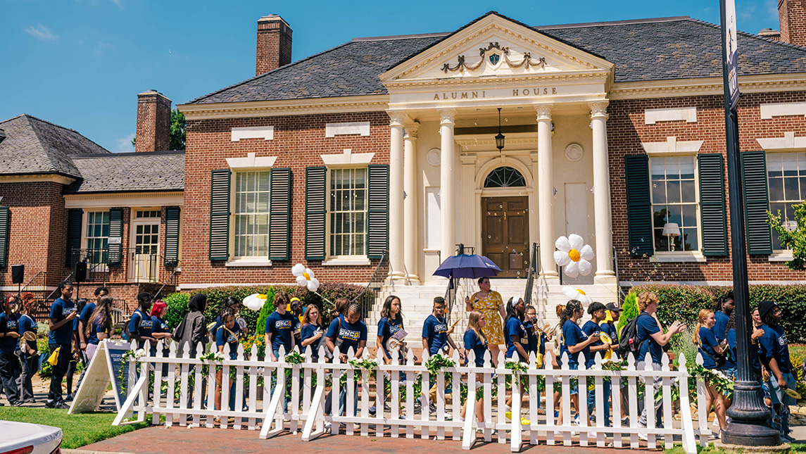 UNCG students tie daisies to a fence outside the Alumni House.