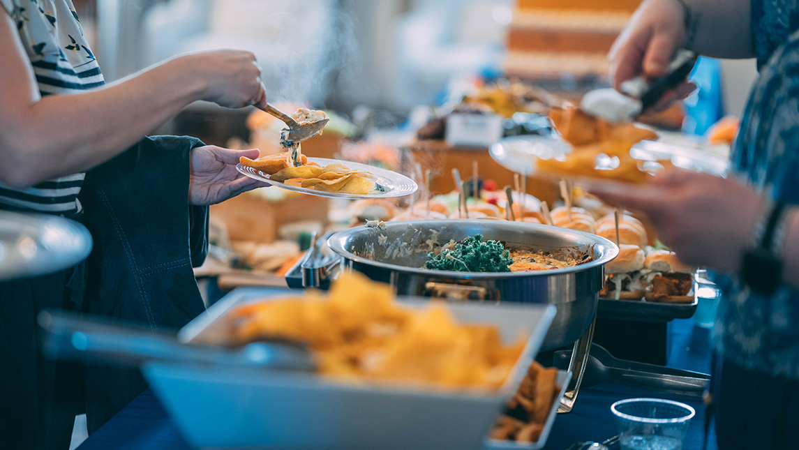 Guests take food from a table at a UNCG event.