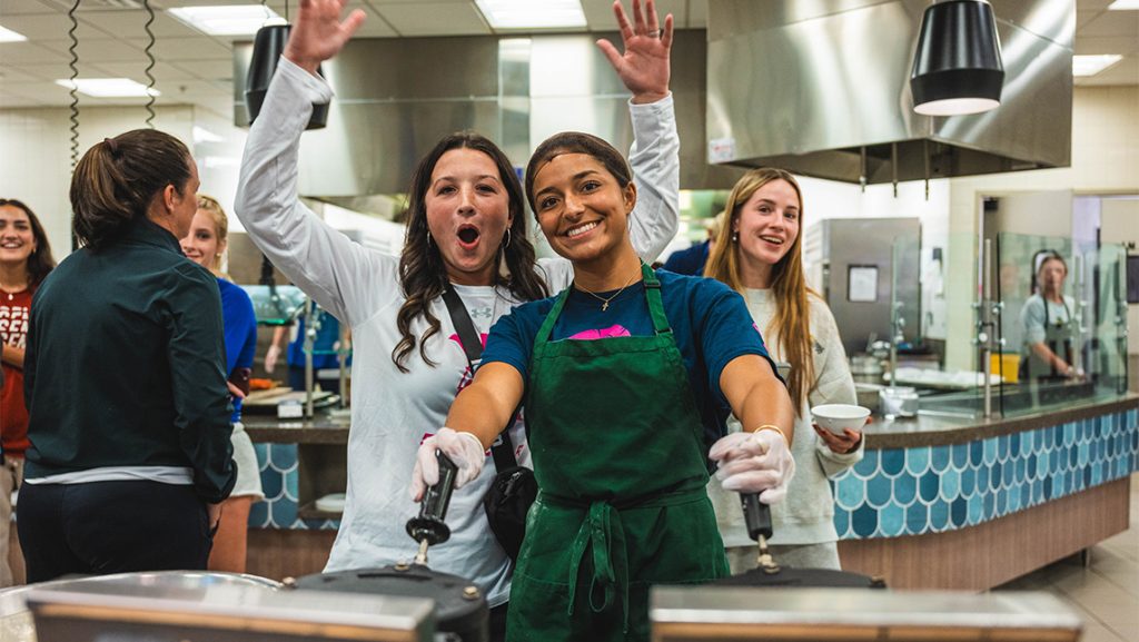 UNCG women's soccer players cheer while cooking.