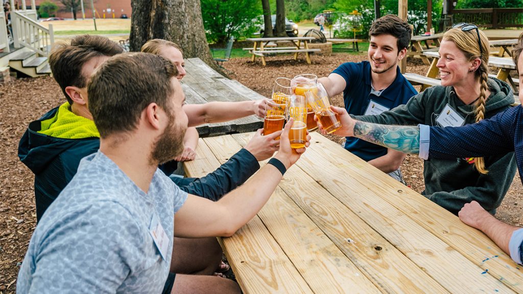 UNCG alumni clink beer mugs together.