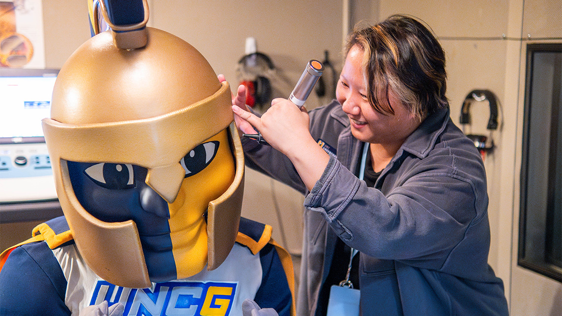A Speech and Hearing Center aide gives an examination to UNCG mascot Spiro.