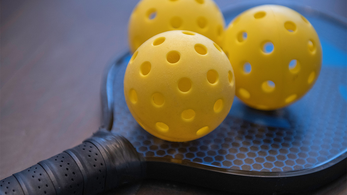 Pickleballs lying on top of a racket.