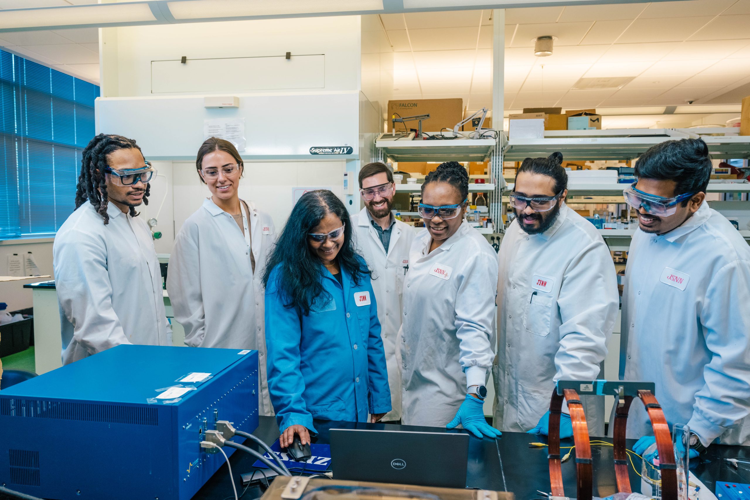 A group of people representing different races work together in a JSNN lab.