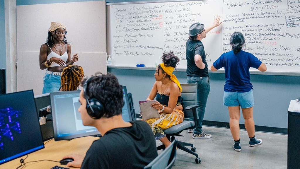 UNCG students talk with their professor at a whiteboard.