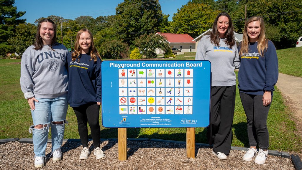 UNCG students stand around an image board at a park.