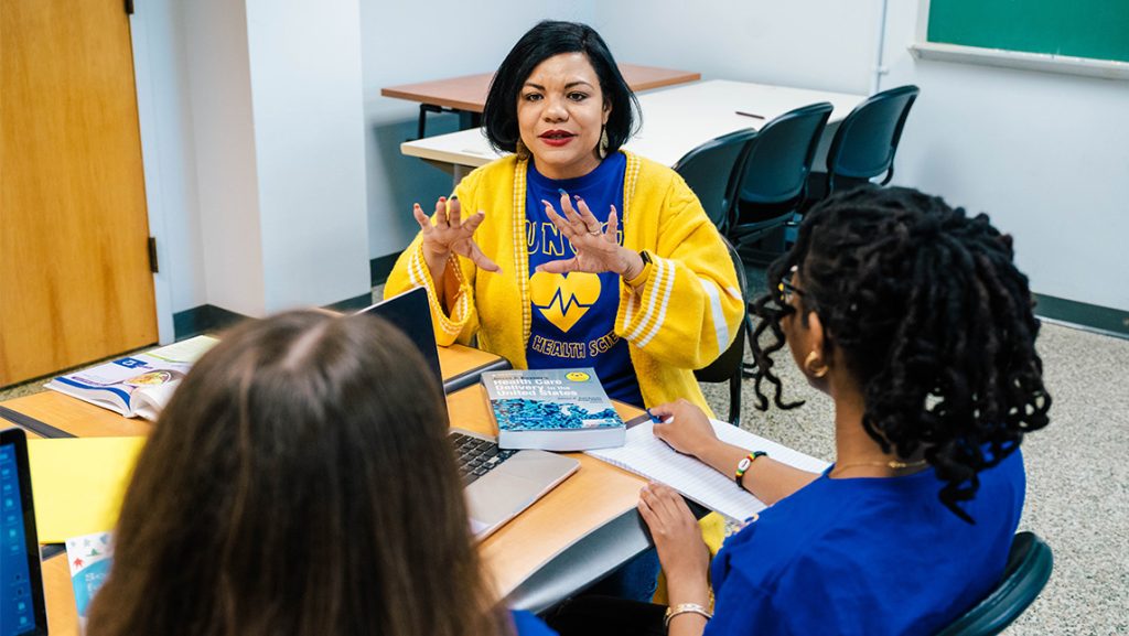 UNCG's Dr. Jeannette Wade talks to students at a desk.