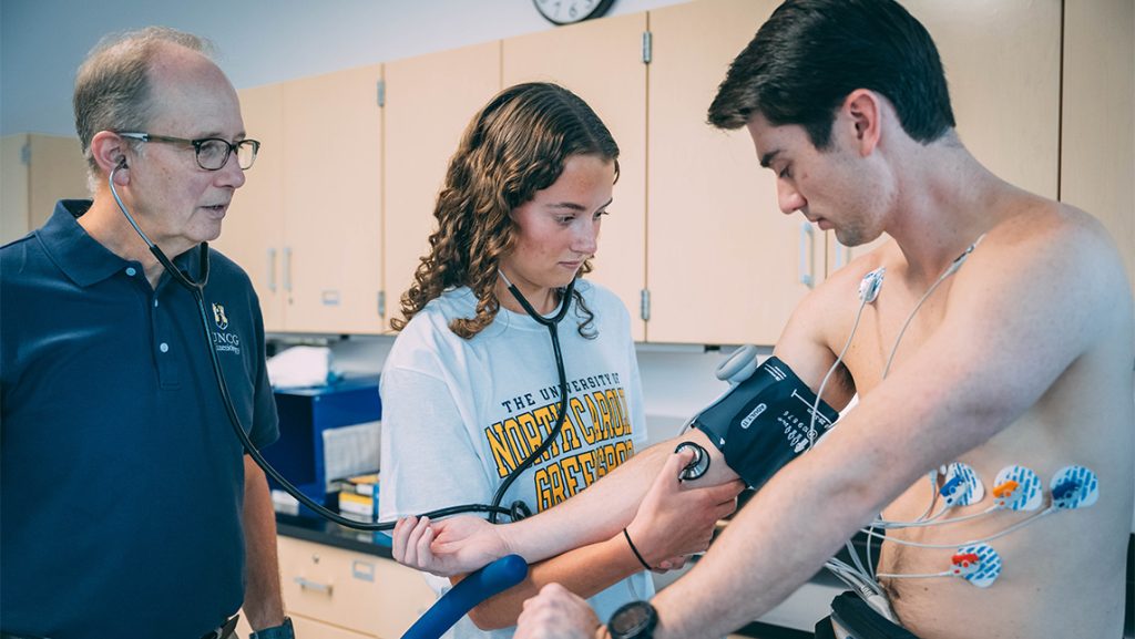 UNCG kinesiology student takes another student's blood pressure.