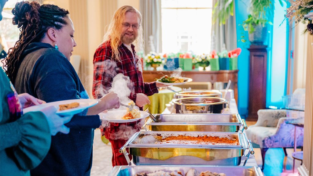 UNCG faculty serve up holiday food from trays.