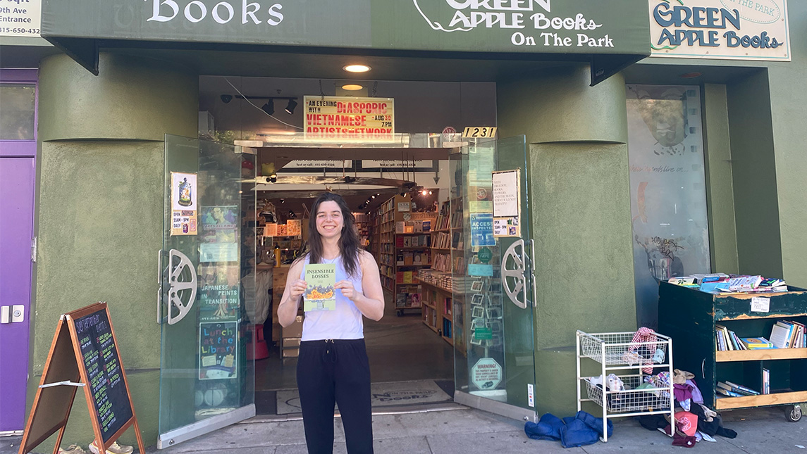 UNCG alumna Dr. Joey Lew stands outside a bookstore holding her book.