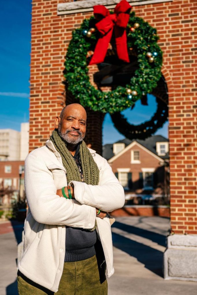 Tony L. Patterson poses beside the UNCG bell tower with a wreath