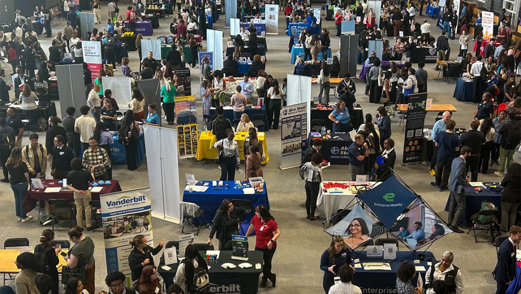Crowd of people looking at booths at a job fair at UNCG.