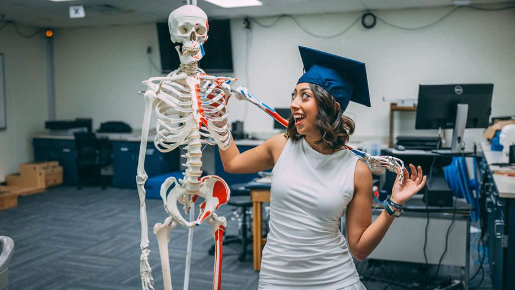 Kat Reyes poses with a kinesiology skeleton model at UNCG.