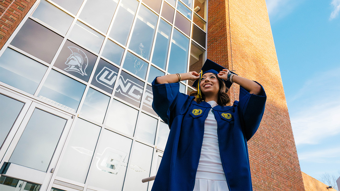 UNCG grad Kat Reyes adjusts her graduation cap.